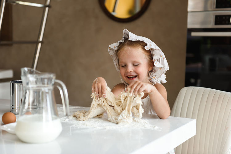 Little girl cooking pizza in the kitchen