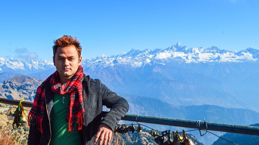 Portrait of young man leaning on railing against mountain