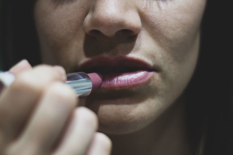 Midsection of woman applying lipstick