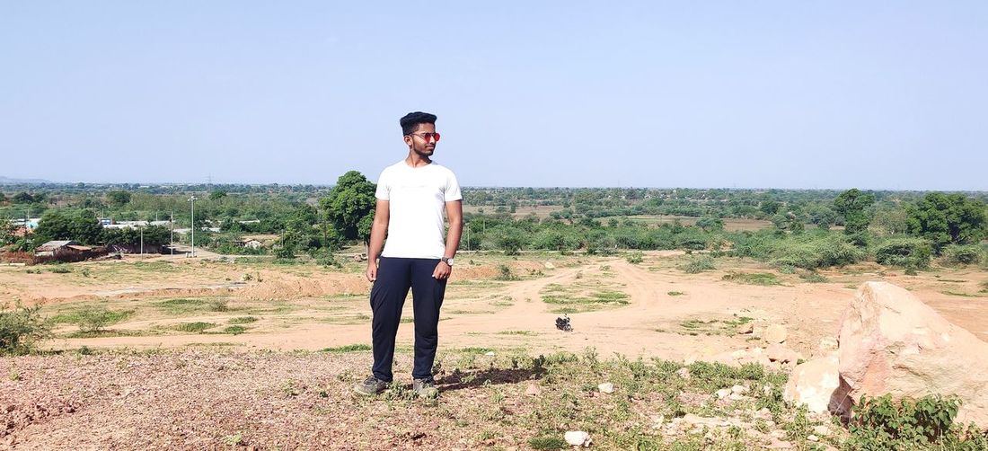 Full length of young man standing on land and have attractive look.