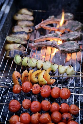 Close-up of meat and fresh vegetables as tomatoes and yellow paprika on barbecue grill
