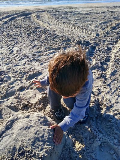 High angle view of cute boy making sandcastle on beach