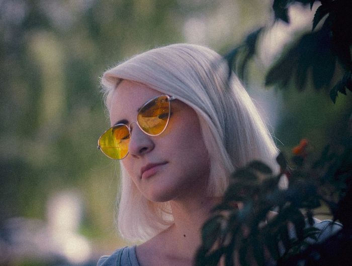 Low angle view of young woman wearing sunglasses at park