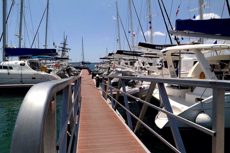 Empty pier amidst yachts moored at harbor