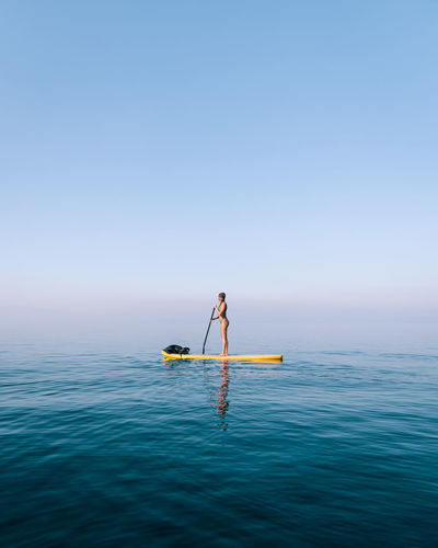Woman paddle boarding on foggy lake on horizon
