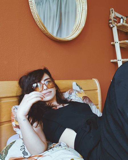 Portrait of woman wearing sunglasses relaxing on bed at home
