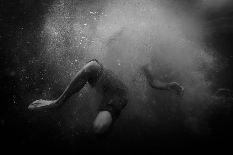Man moving underwater with body surrounded by bubbles