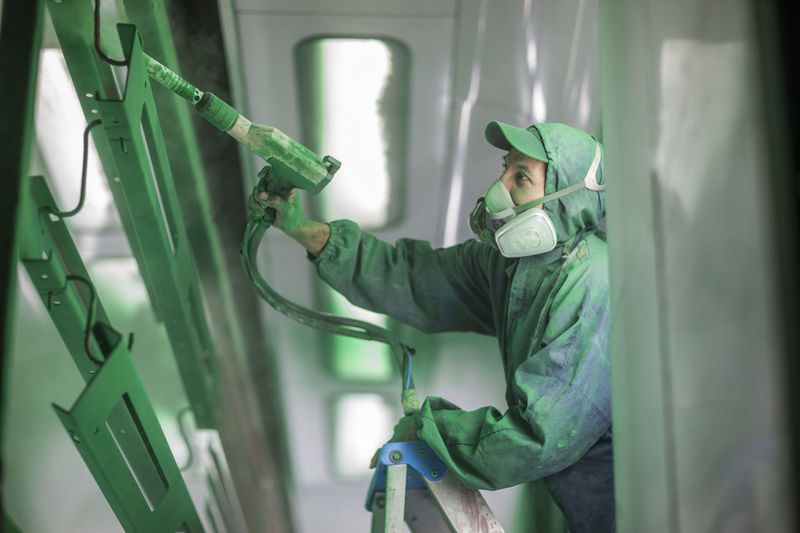 Painters spraying steel components in spray booth of a factory
