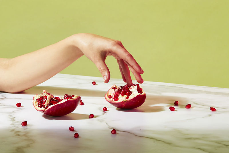 Cropped hand of woman having pomegranate on marble