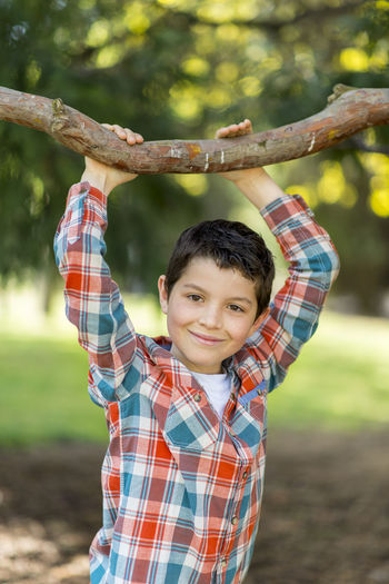 Portrait of boy smiling while holding branch at park