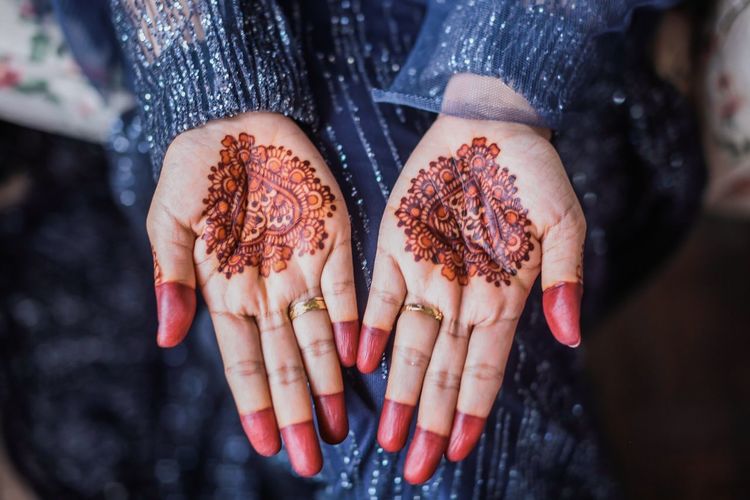 Midsection of woman showing henna tattoo on hands