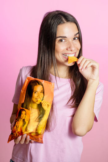 Portrait of young woman drinking milk against pink background