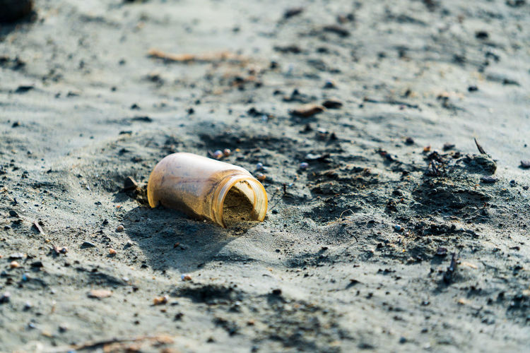 Close-up of abandoned bottle on sand