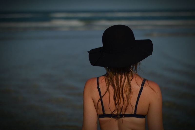 Rear view of young woman in sun hat at sea shore