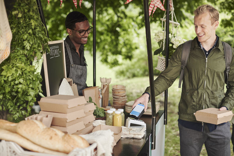 Man paying with cell phone at food stall