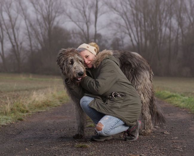 Portrait of woman embracing dog on footpath