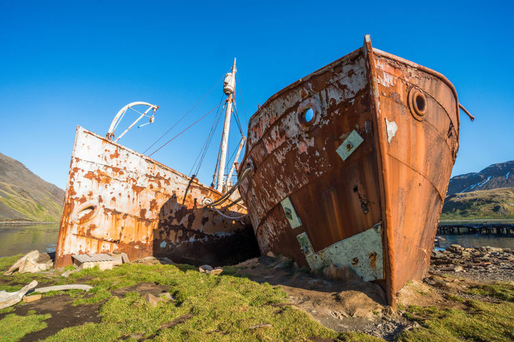 Two rusty old whalers beached on shore