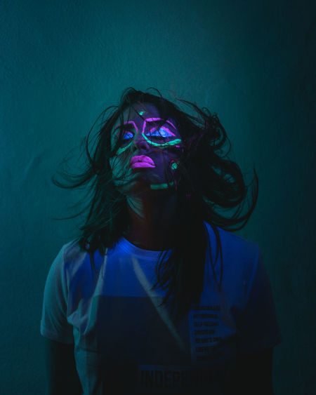 Portrait of young woman wearing mask against gray background