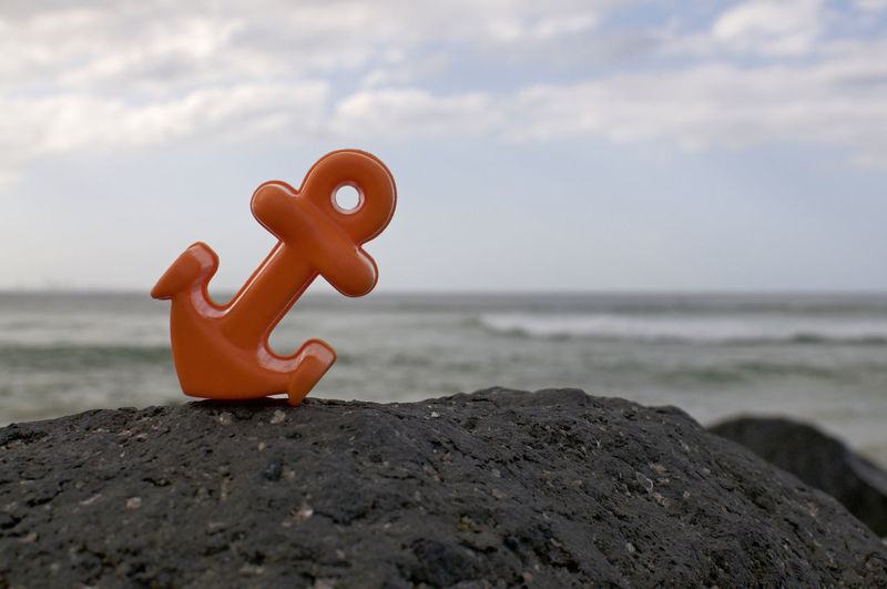 Toy on rock at beach against sky