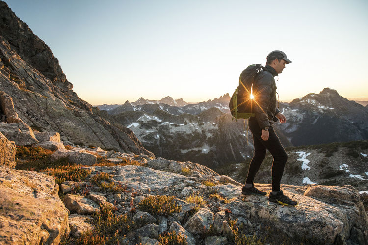 Backpacker hikes across rocky terrain on mountain pass.