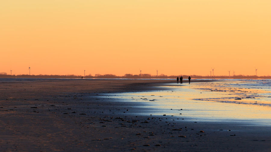 Scenic view of beach against clear sky during sunset