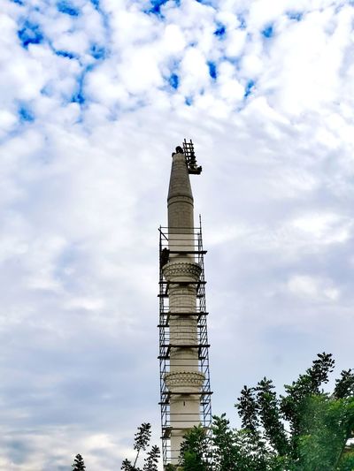 Low angle view of tower by building against sky