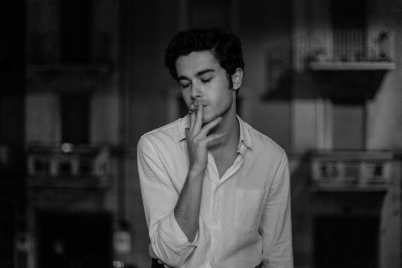 Young man smoking cigarette at home