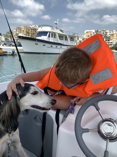 Child with dog on boat in water in cabopino port, southern spain. 