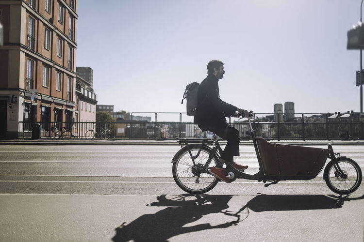 Side view of businessman commuting through cargo bike during sunny day