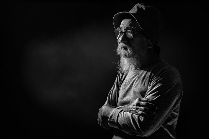Black and white portrait of asian senior man with gray mustache and beard standing