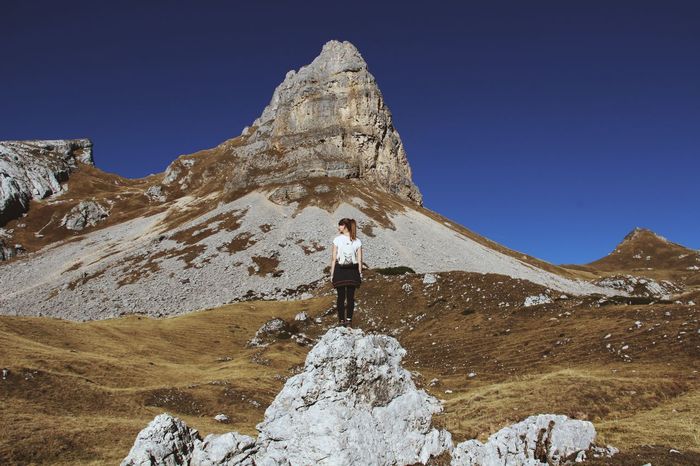 Full length of woman standing on rock against mountain