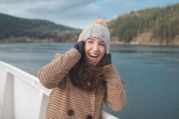 Smiling woman wearing warm clothing standing in boat on sea