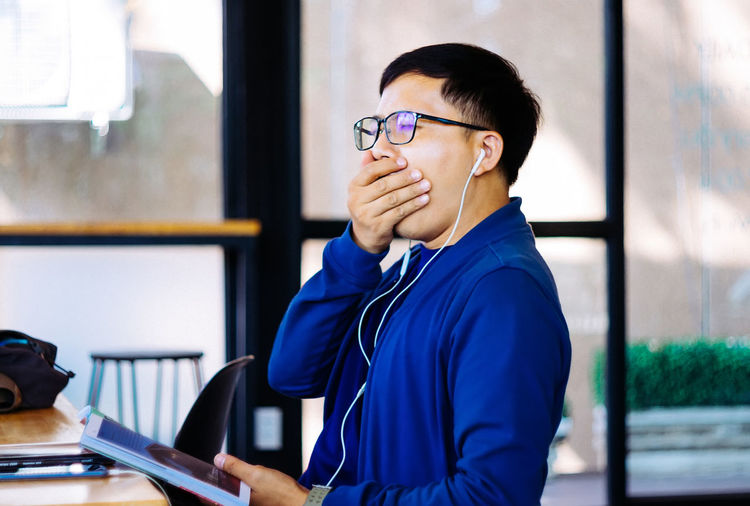 Man listening music while yawning in library