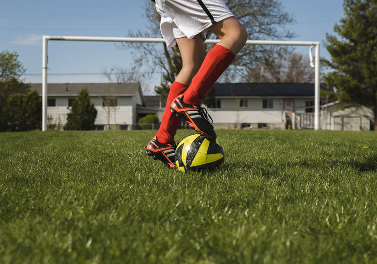 Low section of boy playing with soccer ball on grassy field