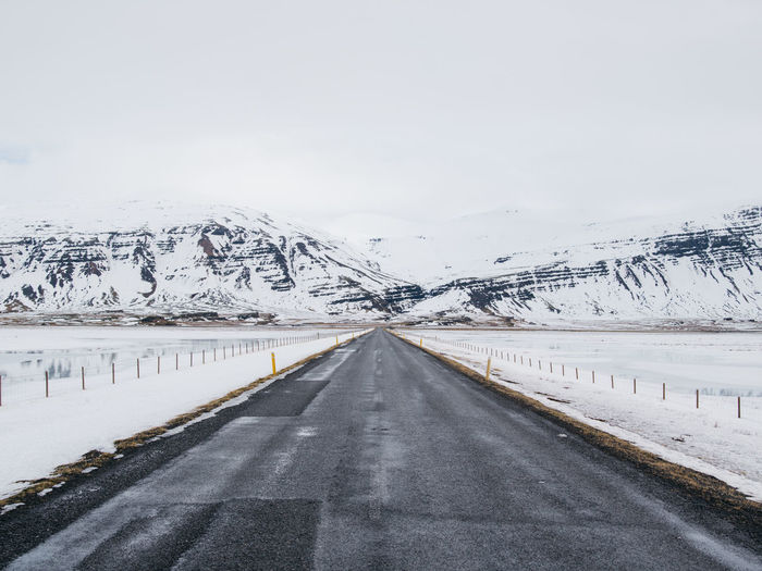 Road amidst snowcapped mountains against sky