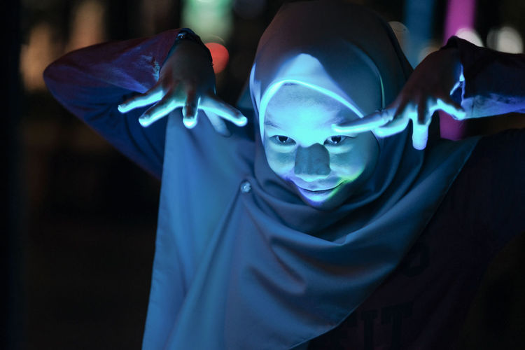 Close-up of spooky woman wearing hijab gesturing outdoors at night