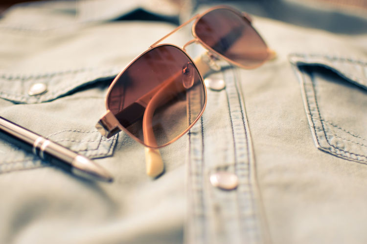 Close-up of sunglasses and pen on shirt