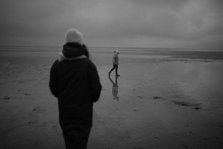 Men walking on beach against sky