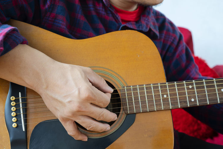 Midsection of man playing guitar