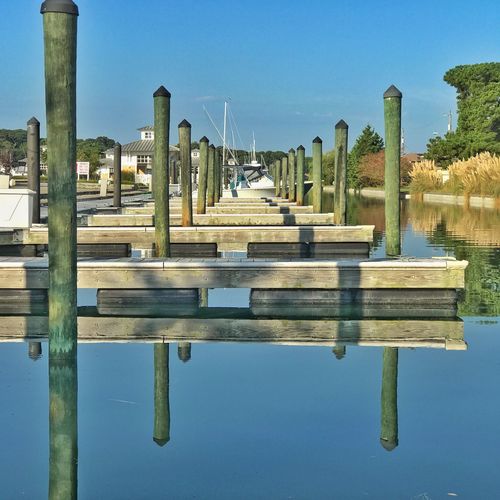 Reflection of built structure in water against clear blue sky
