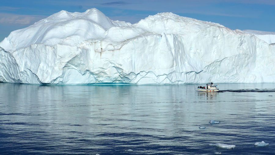 A boat in front of an iceberg on the coast of greenland in the davis strait