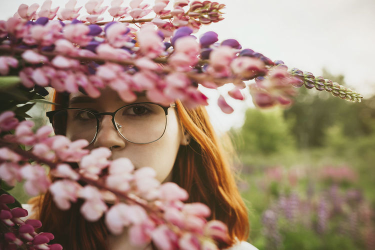 Teenage girl holding bouquet of lupin flowers over face