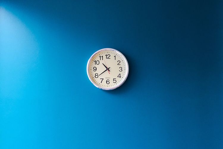 Low angle view of clock against blue background