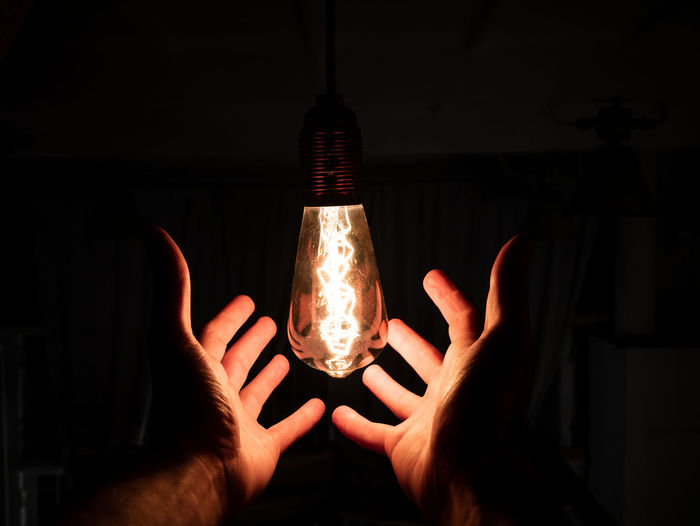 Close-up of hand holding illuminated light bulb