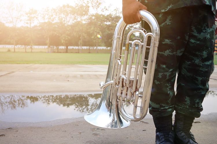 Midsection of army soldier holding saxophone