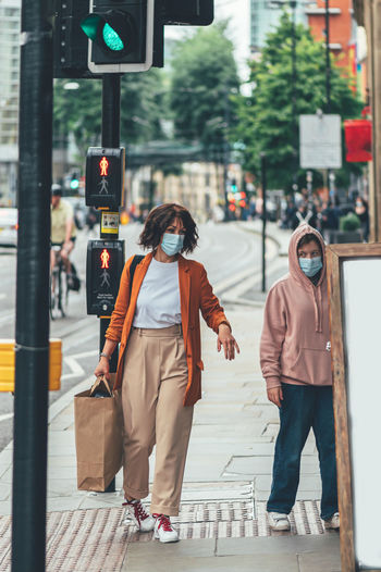 Mum and daughter in face mask are shopping in city centre of manchester, england, uk , new normal