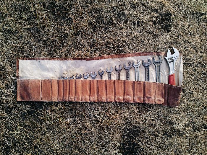 Directly above view of various hand tools arranged in pouch on field