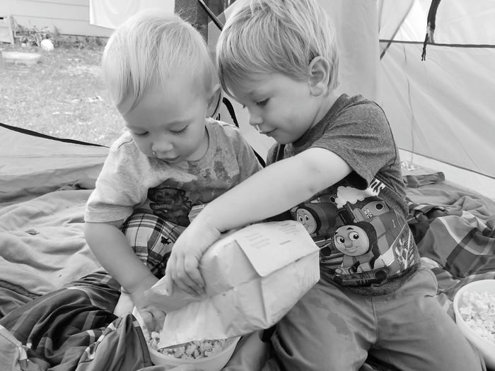 Brothers removing popcorn from paper bag