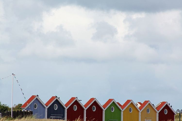 Multi colored beachhouses against sky