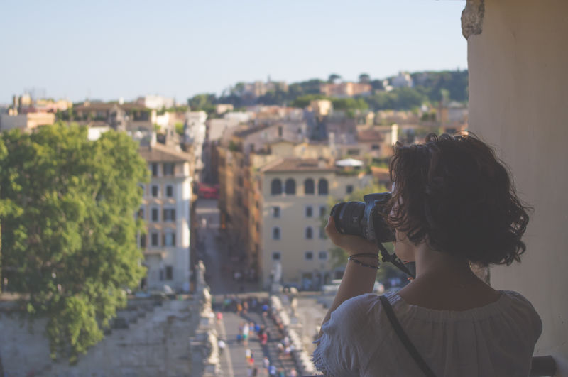Rear view of woman photographing cityscape